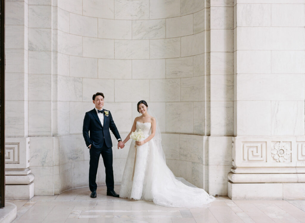 Bride and groom portrait in tux and lace Monique Lhuillier wedding gown at New York Public Library