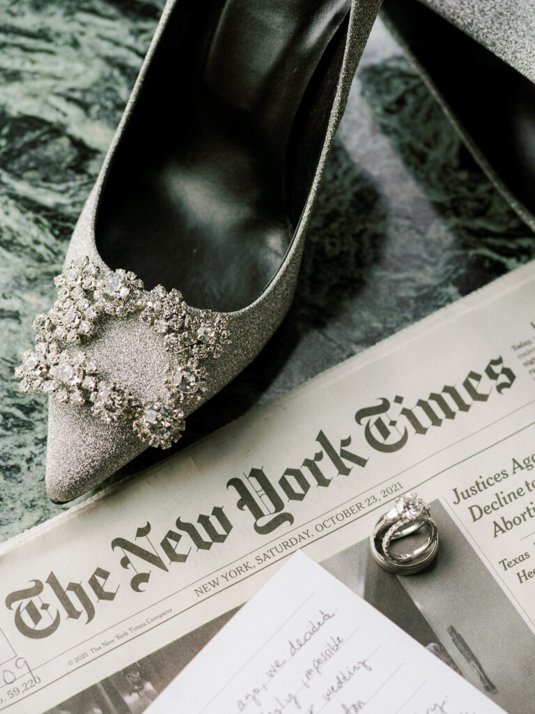 Roger Vivier wedding shoes with rhinestone detail on New York Times newspaper with wedding rings