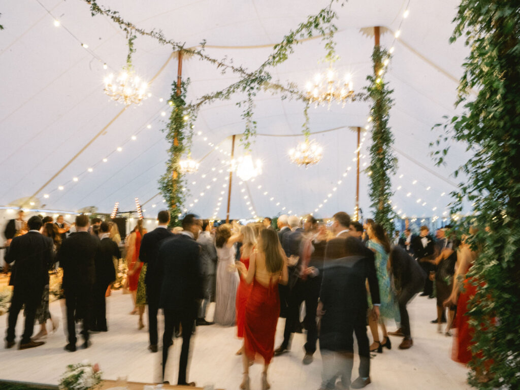 sailcloth wedding with chandeliers and greenery dance floor with guests 