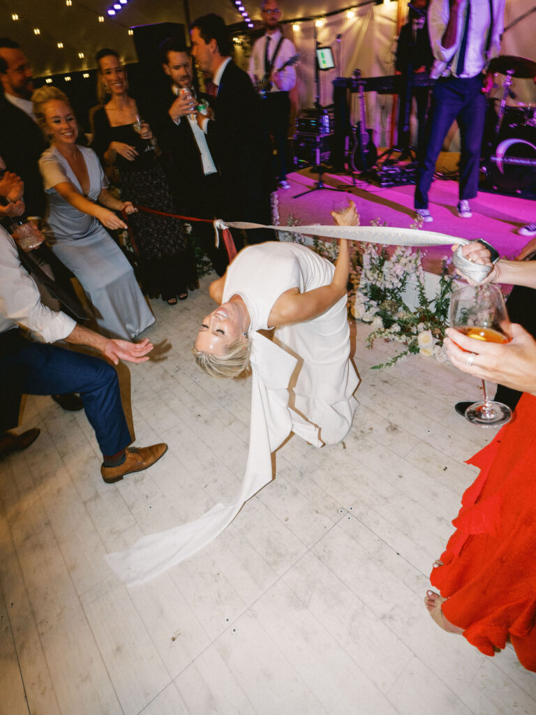 bride doing limbo dancing at wedding reception 