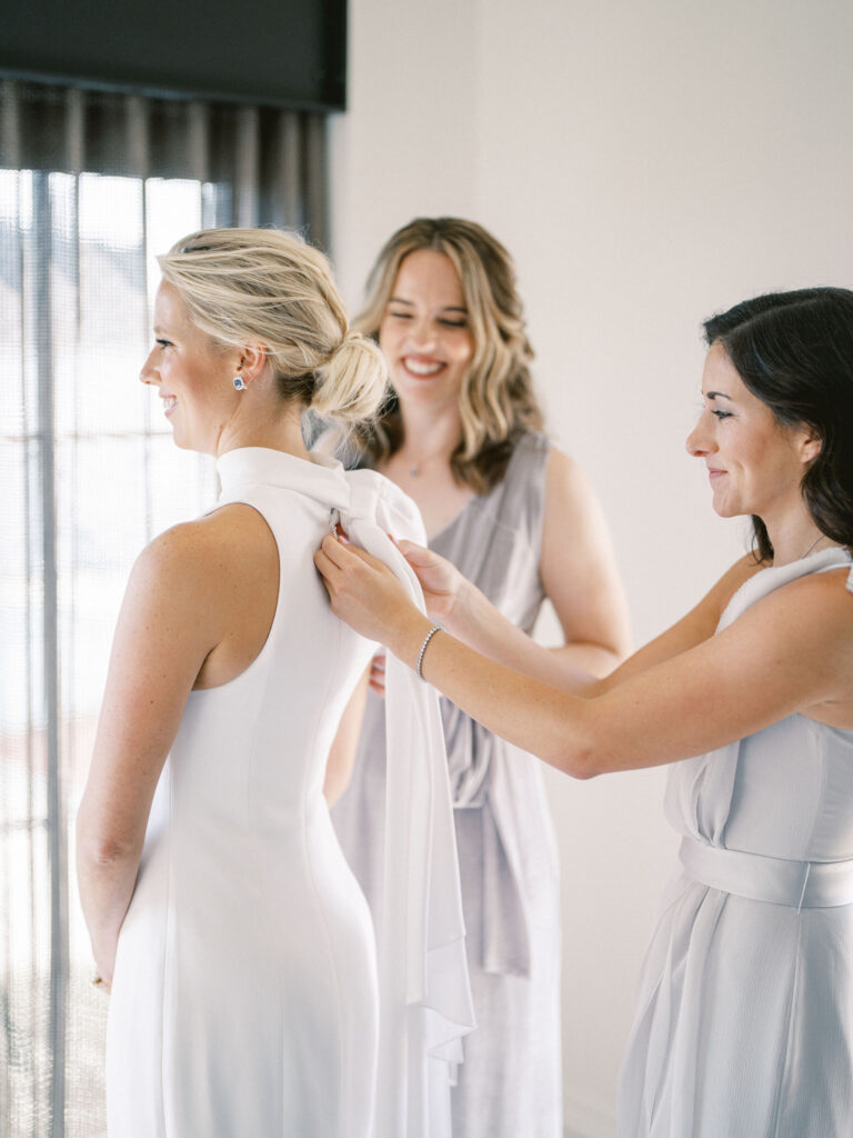 bridesmaids helping bride get dressed on wedding day at sagamore pendry 