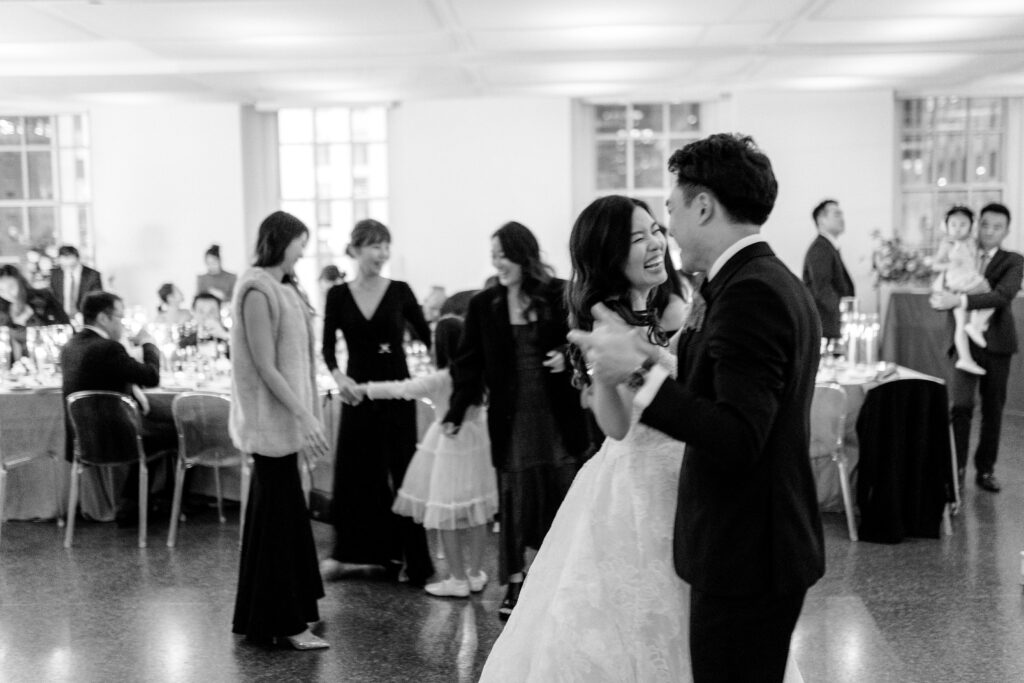 Bride and groom dancing at their wedding reception and laughing in black and white 