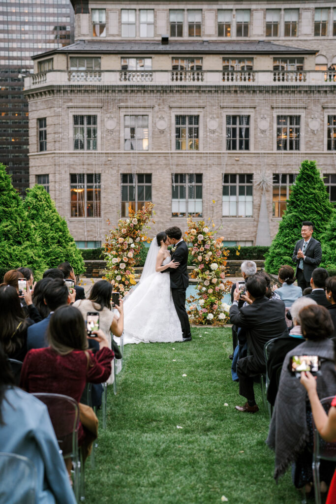 Bride and groom kissing after wedding ceremony on rooftop garden wedding in New York City 