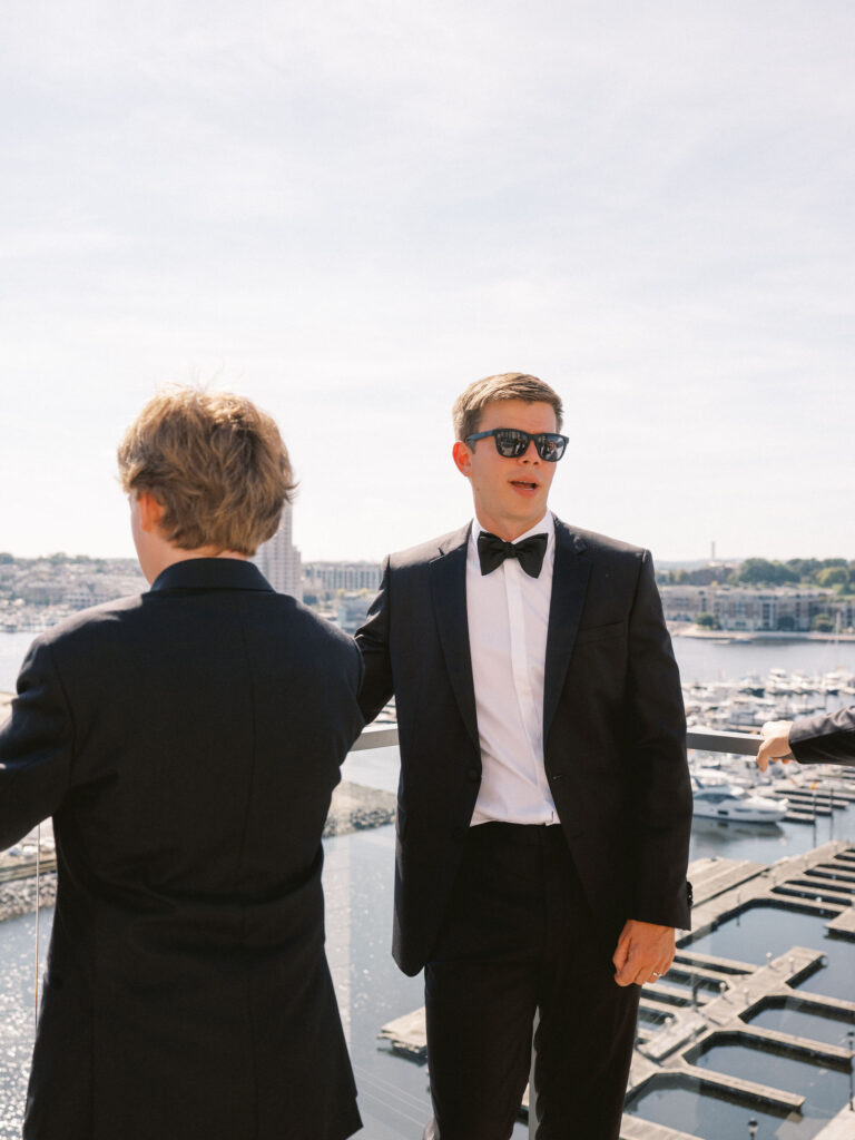 groom in tux and sunglasses at sagamore pendry hotel in baltimore overlooking inner harbor 