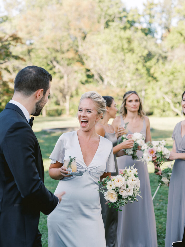 bridesmaid in blue dress laughing and smiling holding bouquet 