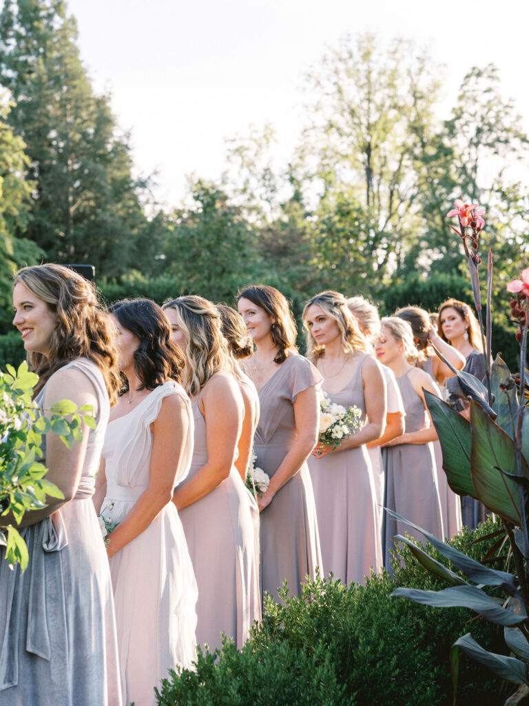 bridesmaids during wedding ceremony in mismatched pastel jenny yoo dresses 
