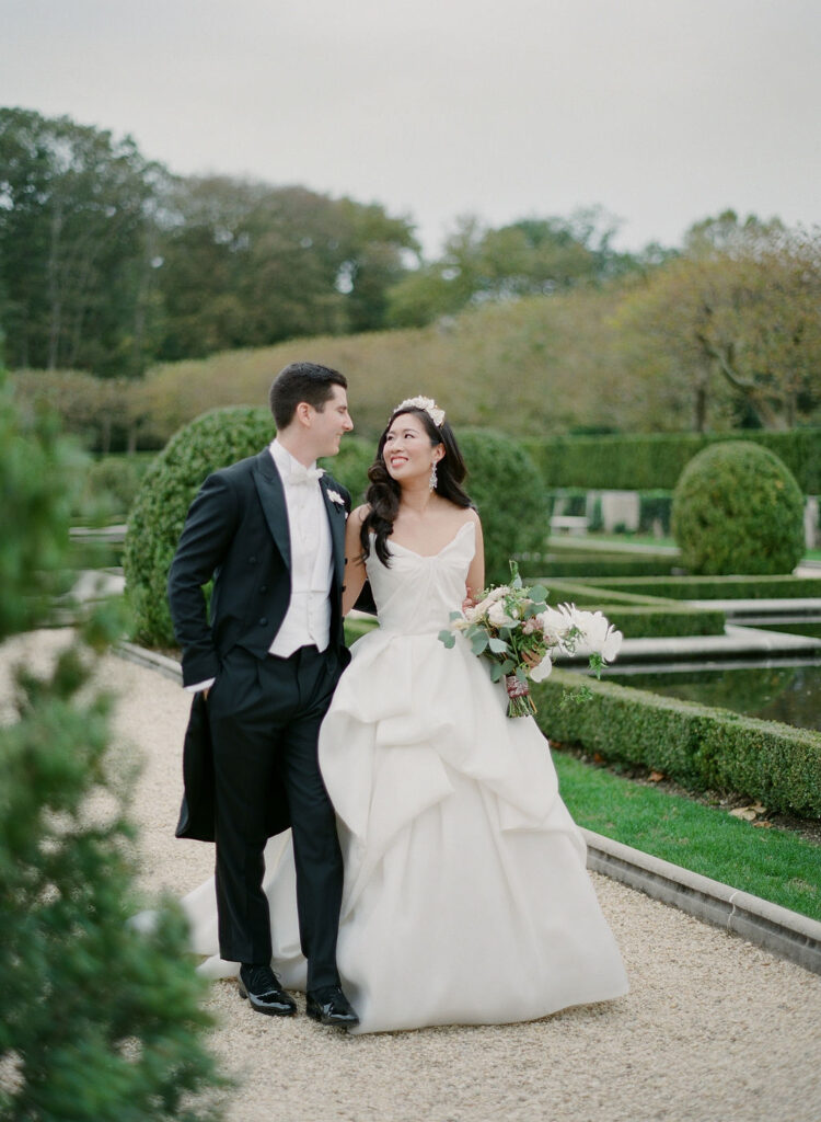 laughing bride and groom in gardens of Oheka Castle in new york bride wearing strapless monique lhuillier ballgown 