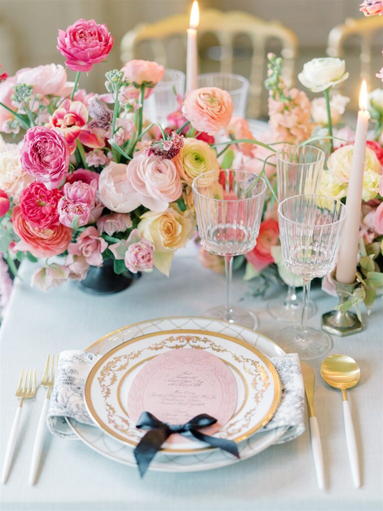 Wedding place setting with pink floral centerpiece and gold embellished plates