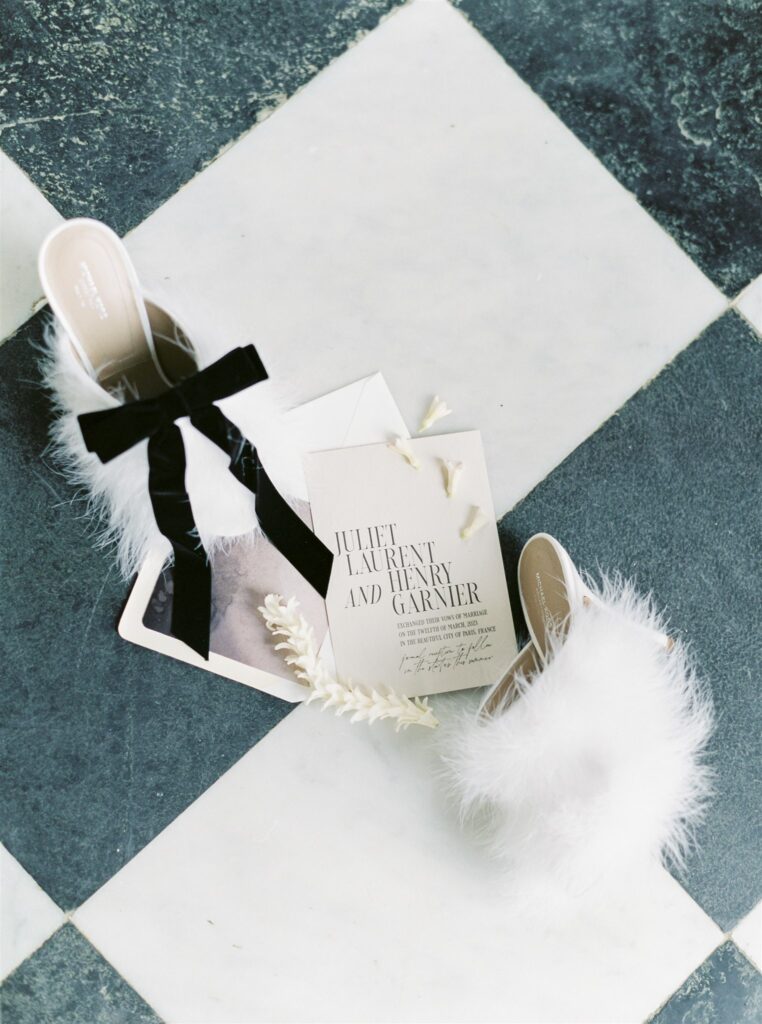 Wedding detail flatlay with white feather shoes and modern wedding invitation 