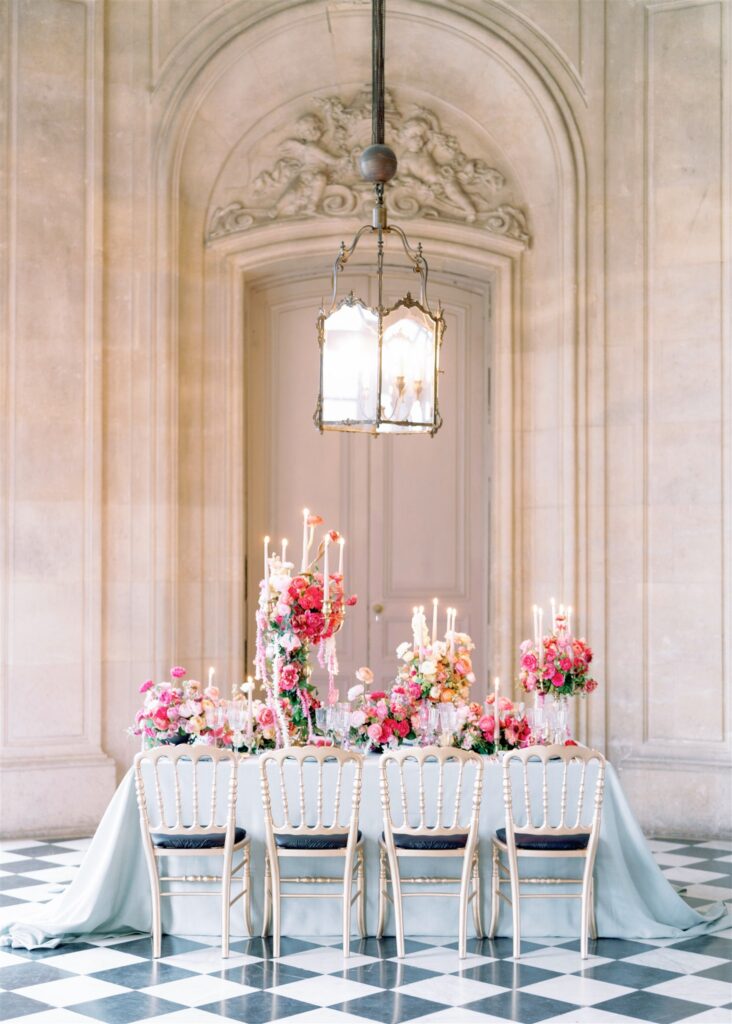 Intimate wedding tablescape at Château de Champlâtreux with bright pink floral centerpiece and candelabras