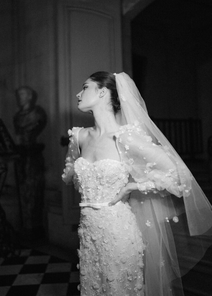 Black and white flash photography of bride wearing floral applique dress and long veil 