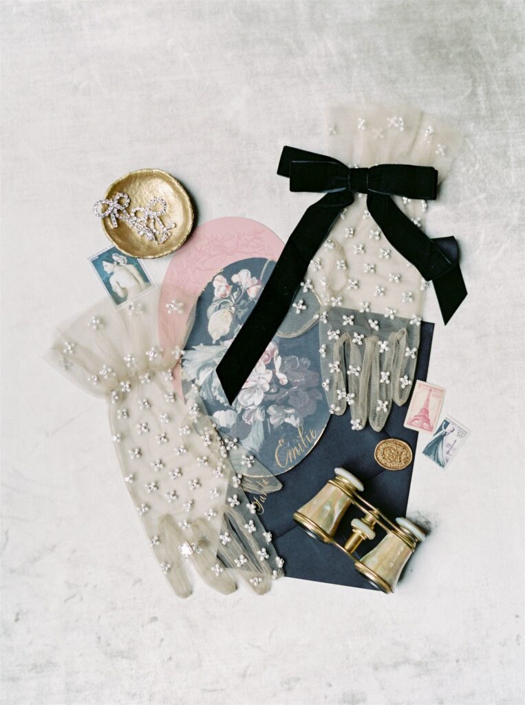 Wedding detail flatlay with rhinestone gloves and antique French binoculars 