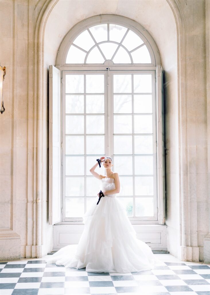 full length bridal portrait in front of bright window at Château de Champlâtreux with black and white checkered floor