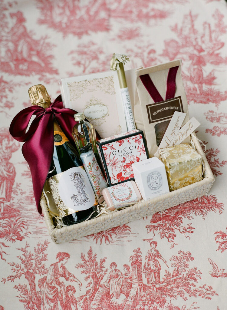 welcome basket for wedding with gucci red floral print and red toile fabric background styled by east made co wedding designer 