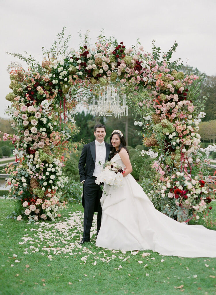 bride and groom under floral arch 