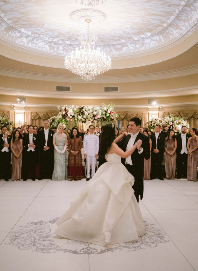 bride and groom first dance in ballroom with custom monogram dance floor 