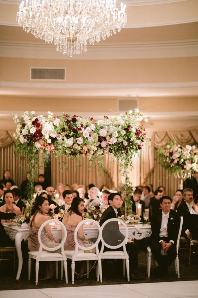 guests at dinner in ballroom with elevated rose centerpiece 