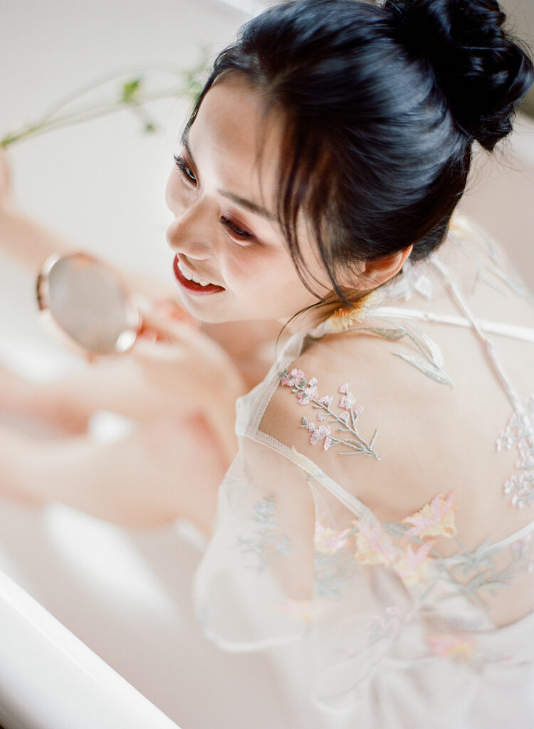 bride laughing in bathtub getting ready on wedding day 