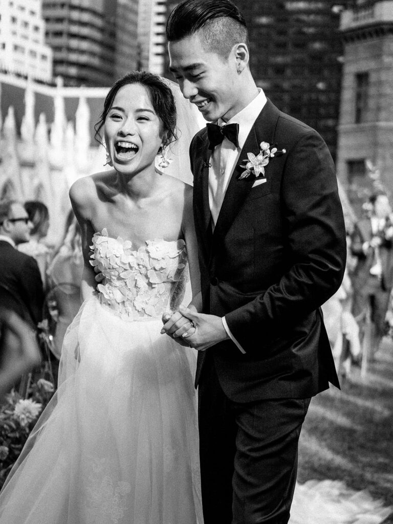bride and groom laughing in black and white after their wedding ceremony 