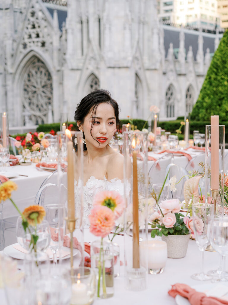 bride sitting at table with taper candles and coral flowers 
